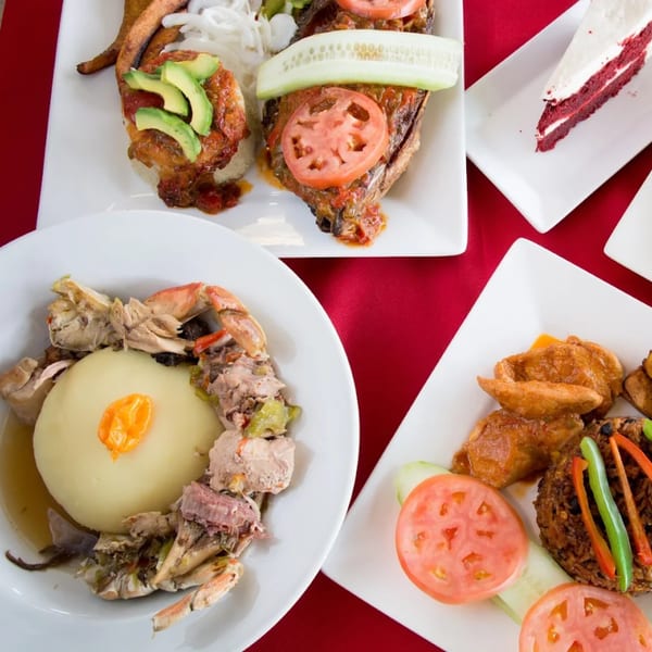 An overhead view of various African dishes, including fish, fufu with crab, and red velvet cake.