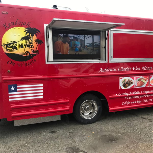 Red Kendejah food truck with a Liberian flag, logo, menu items, and a video playing.