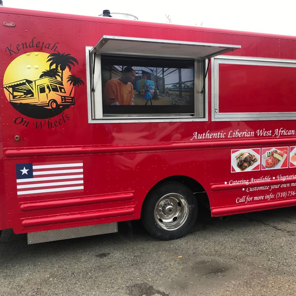 Red Kendejah food truck with a Liberian flag, logo, menu items, and a video playing.