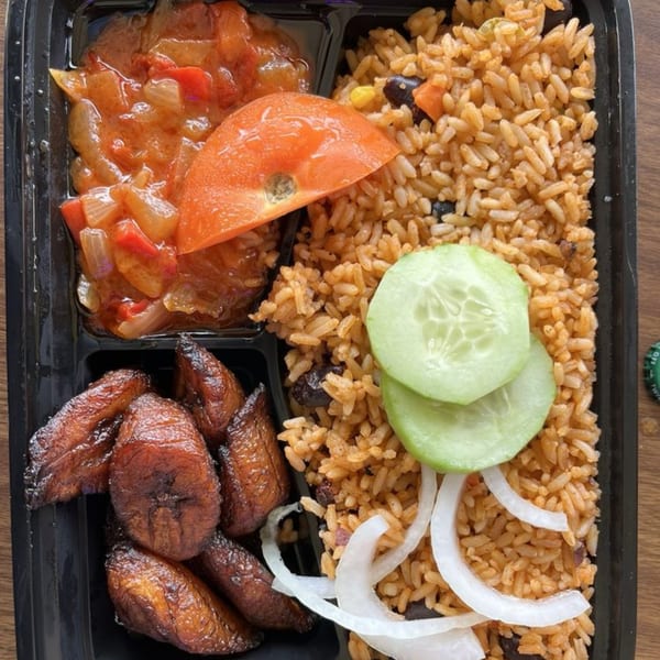 African meal with rice, plantains, stew, tomato, cucumber, and onions in a black container.